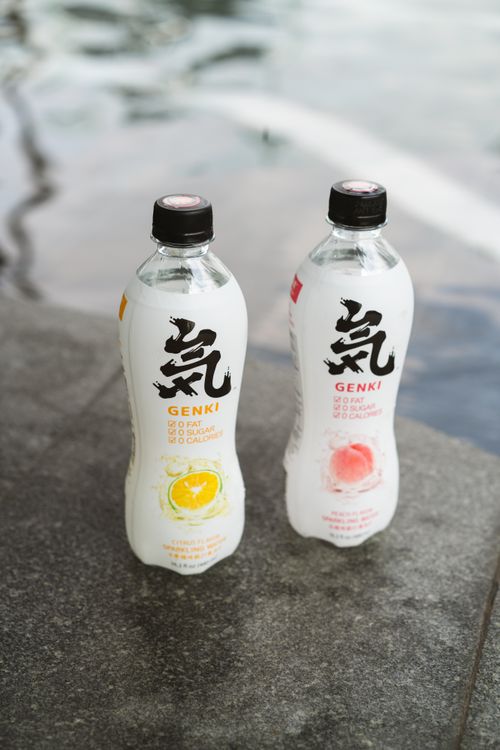 Free Two sparkling water bottles with lemon and peach flavors, styled for product photography near a pool. Stock Photo