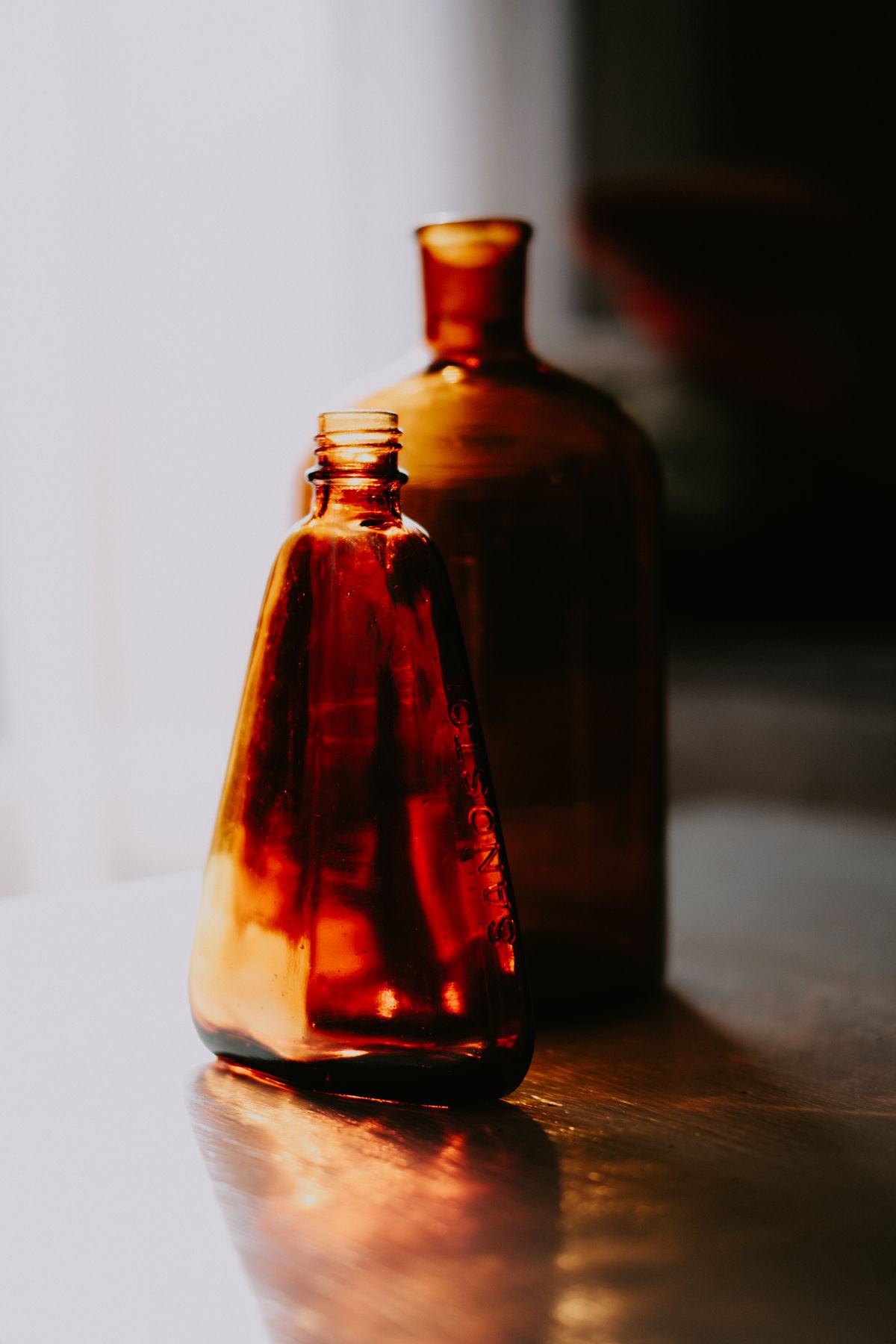 Amber apothecary glass bottles in warm light — photo by Mathias Reding on Pexels