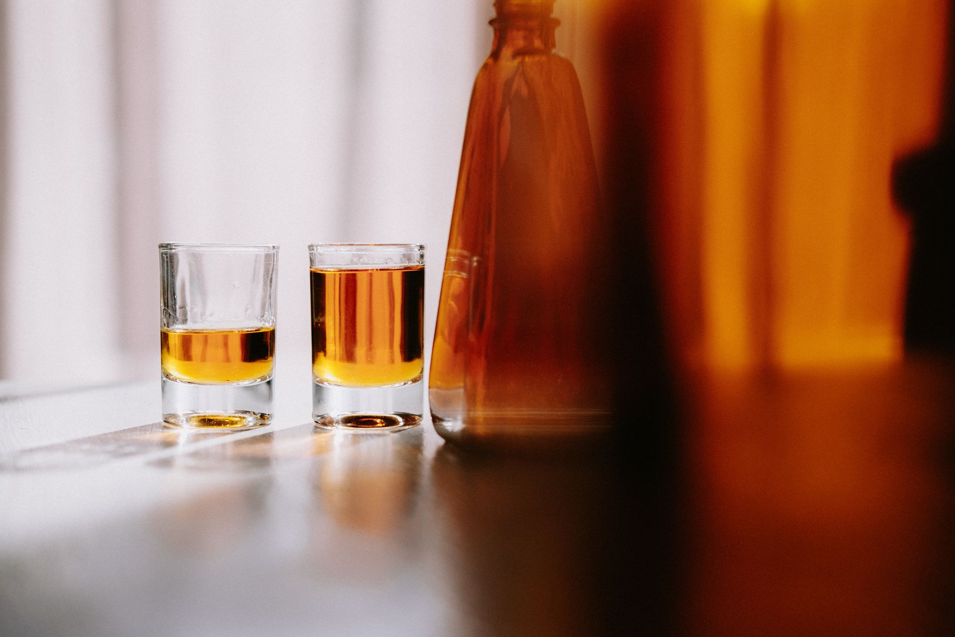 Person pouring whiskey into a glass with ice