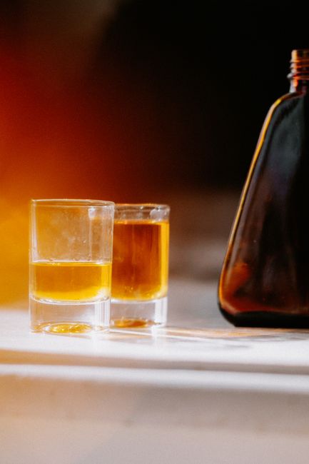 Two whiskey glasses and a bottle catch sunlight, creating a warm, inviting ambiance.
