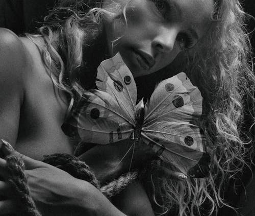 Grayscale Photo of a Woman Holding a Butterfly