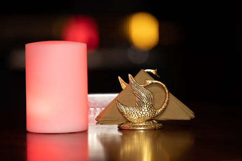 A Candle Beside Gold Holder with Tissue on a Brown Surface