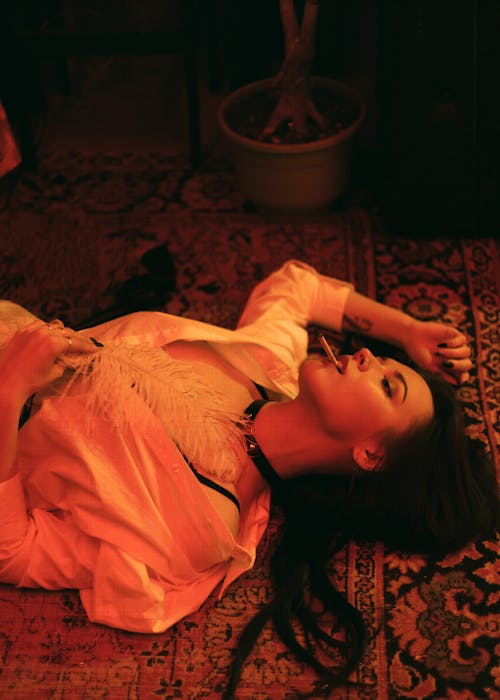 A Woman Lying Down on the Floor while Smoking