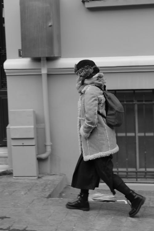 Grayscale Photo of a Woman in a Jacket Walking