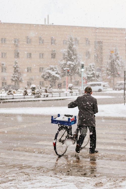 Man with Bicycle Crossing Street during Snowstorm