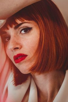 Close-up portrait of a redheaded woman with striking red lips and expressive eyes.