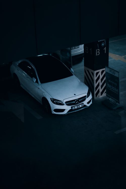 Free High angle shot of a white Mercedes Benz parked in an indoor parking garage. Stock Photo