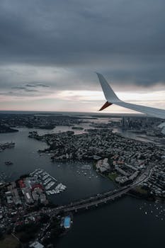 A captivating aerial shot showing Sydney's cityscape through an airplane window with a moody sky.