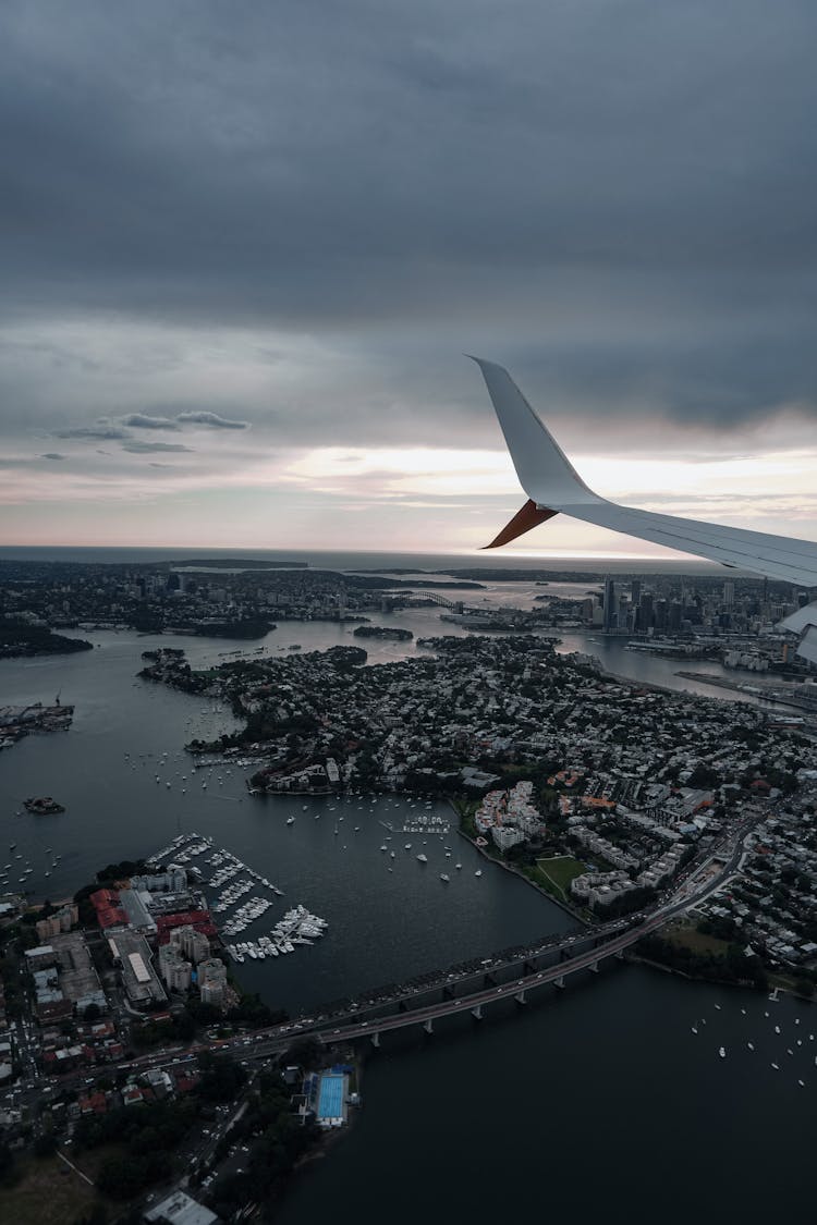 White Airplane Wing Over City Under Gloomy Sky