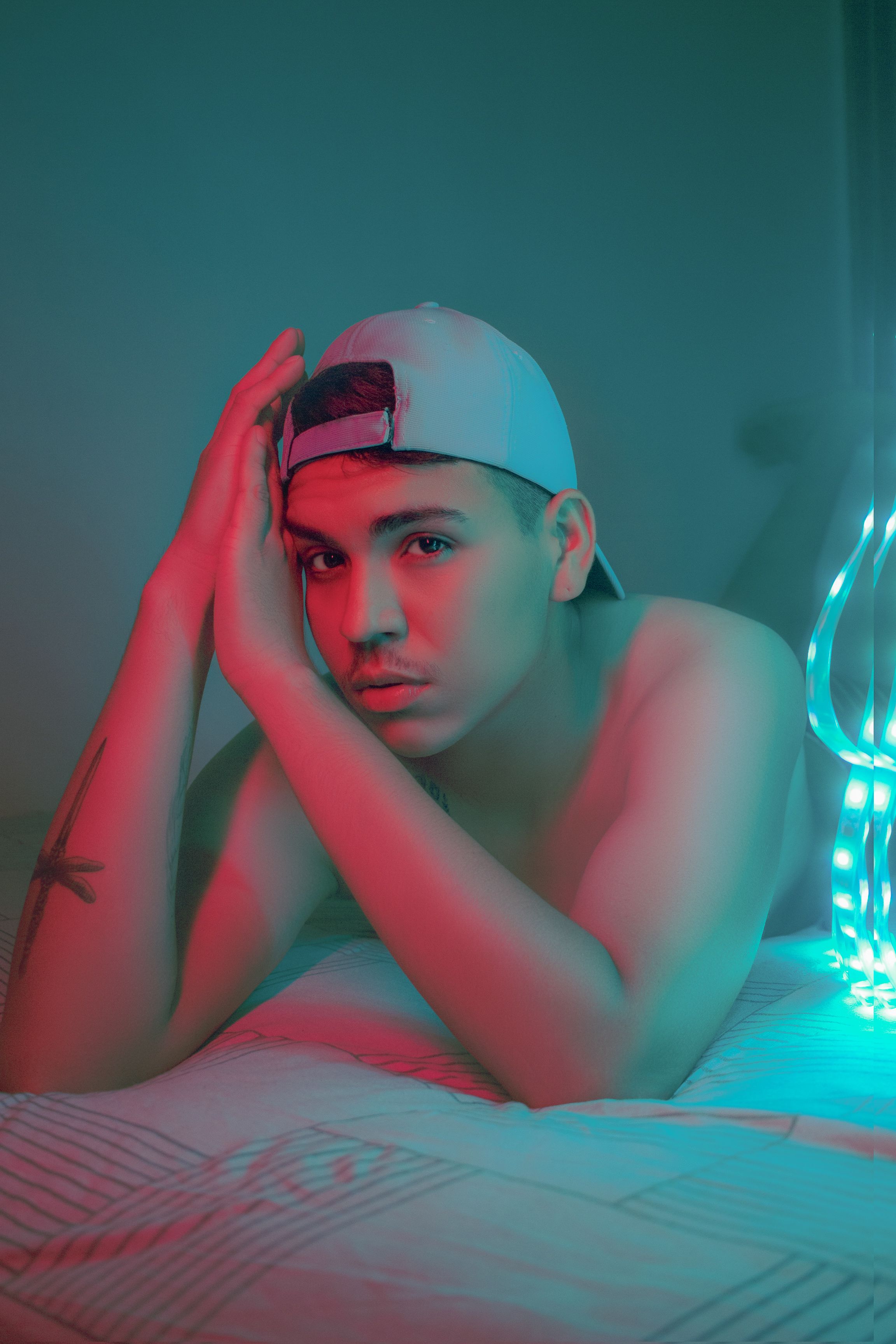 A creative portrait of a tattooed man in intense neon lighting creates a modern, artistic atmosphere.