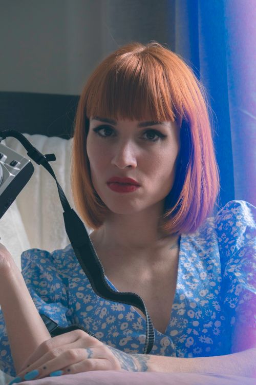 Free Moody portrait of a woman with red hair holding a vintage camera. Stock Photo