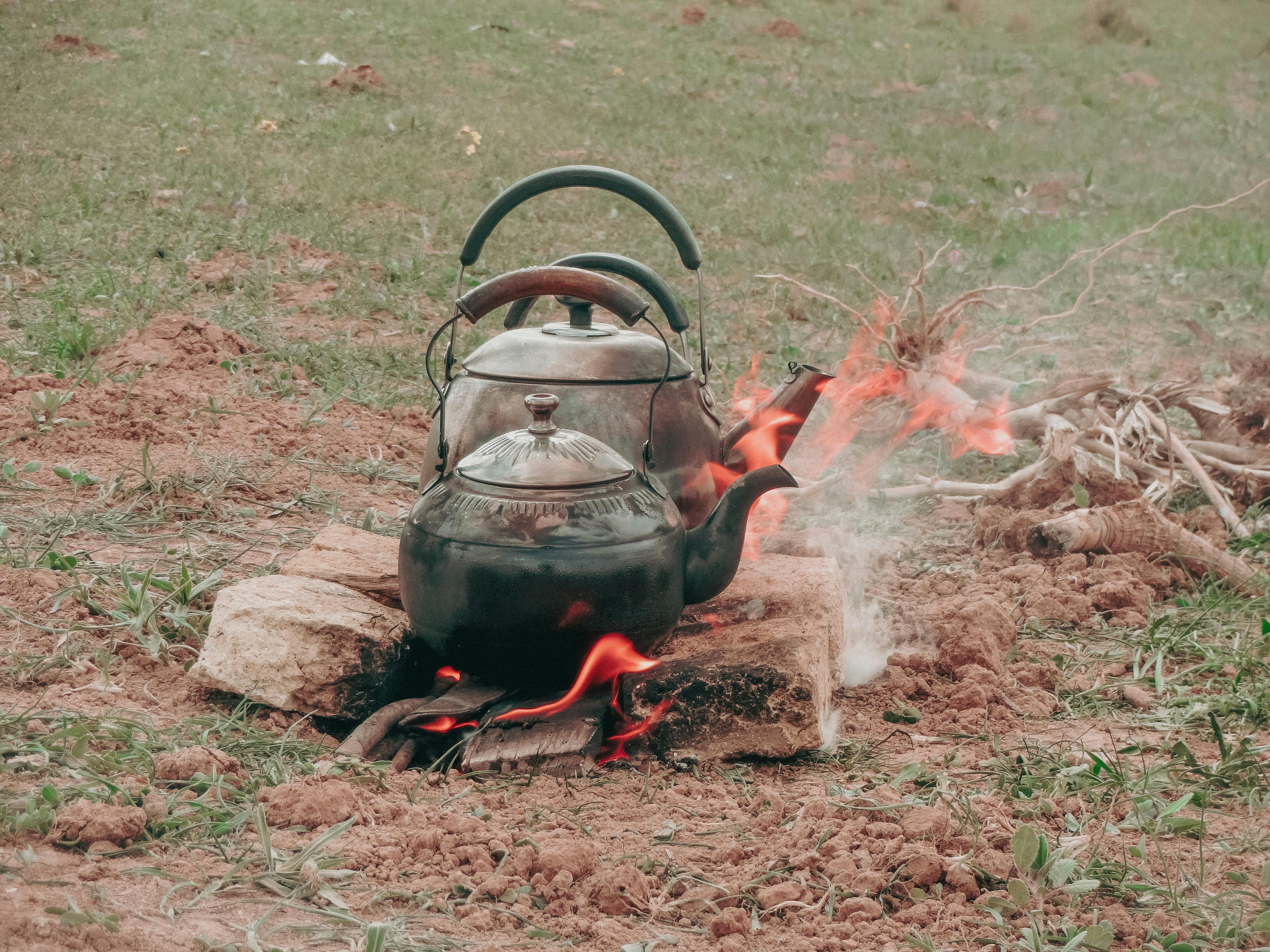 Kettles on Fire Lit in Grass Field · Free Stock Photo