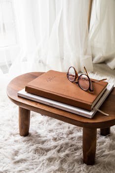 A cozy living room setting with a book and eyeglasses on a small wooden table.