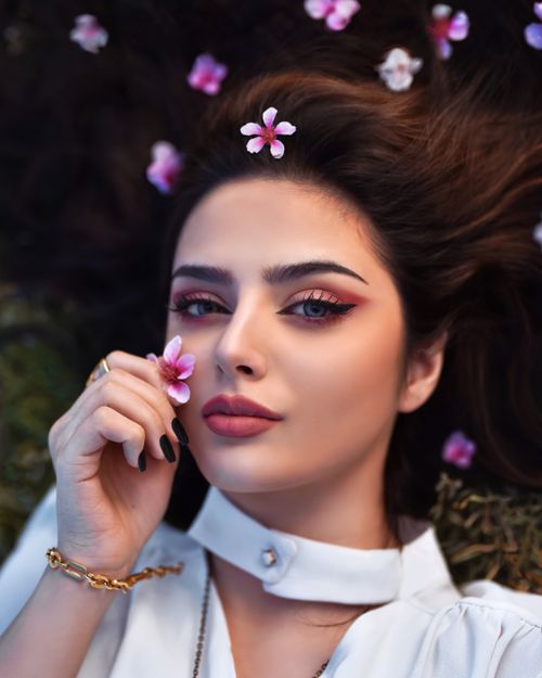 Free Elegant portrait of a brunette woman lying with flowers, conveying beauty and grace. Stock Photo