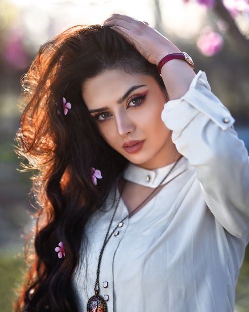 Free Captivating portrait of a woman outdoors, adorned with flowers, showcasing elegance and style. Stock Photo