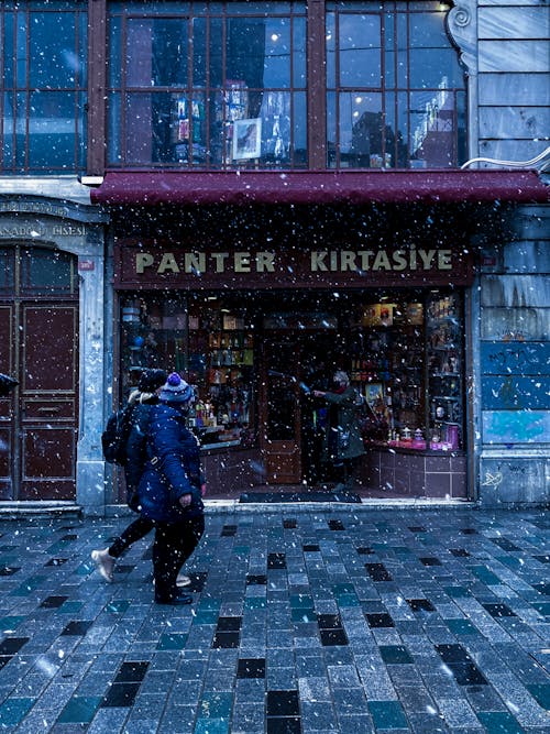 People Walking on the Sidewalk at Snowfall 