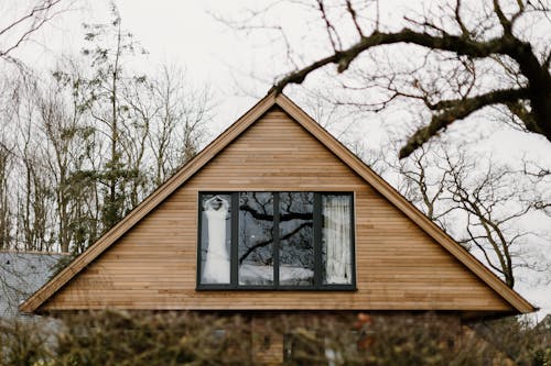 
A View of the Window of a Wooden House with a Hanged Wedding Dress