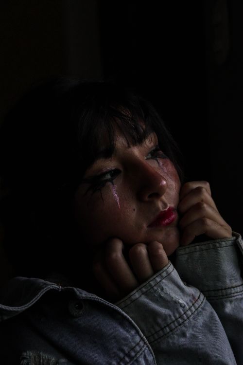 Free Moody portrait capturing a woman with tear-streaked makeup in low light, conveying sadness. Stock Photo