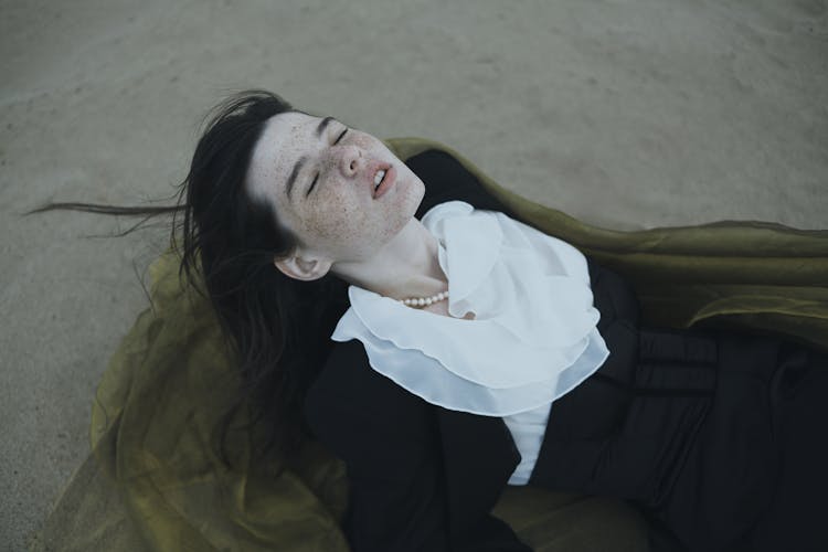 Girl With Freckles Lying On Back On Sand With Eyes Closed