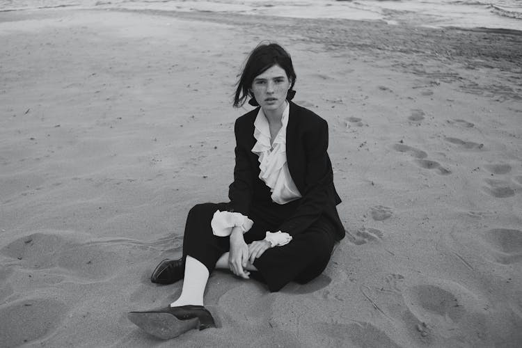 Young Woman In Formal Outfit Sitting On Beach