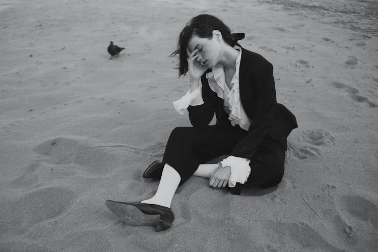 Young Brunette Woman In Formal Outfit Sitting On Sand