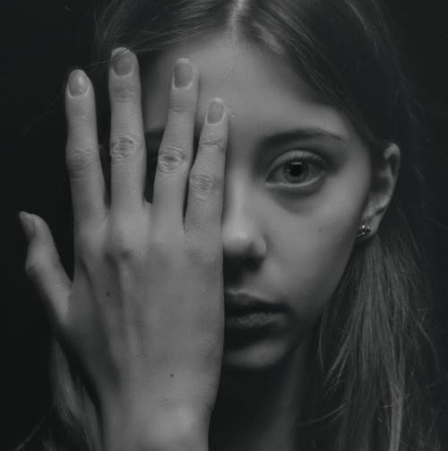 Фотография женщины, закрывающей лицо рукой в оттенках серого