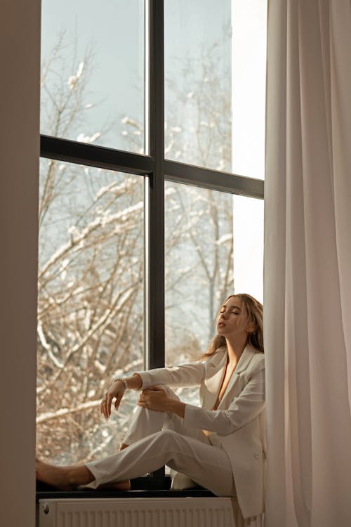 Free Woman in White Business Outfit Sitting on Window Sill Stock Photo
