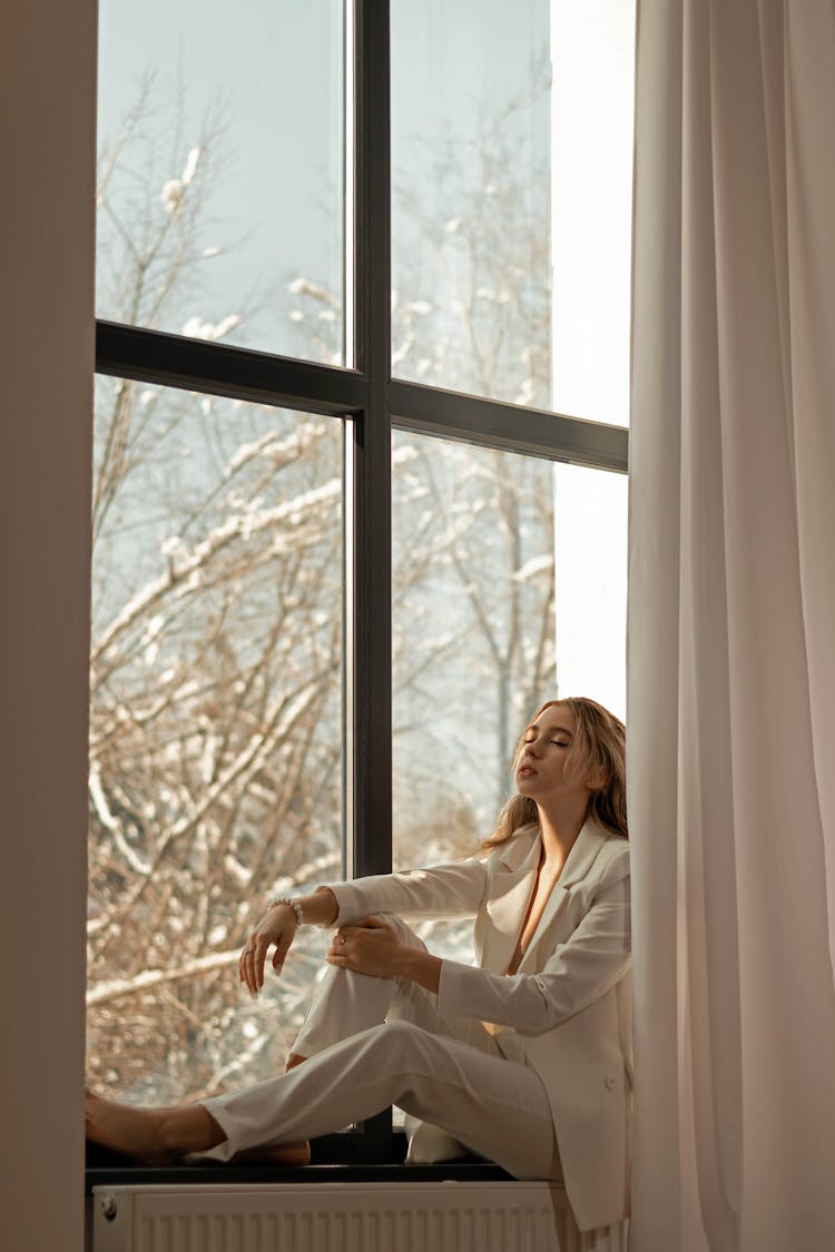 Woman In White Business Outfit Sitting On Window Sill