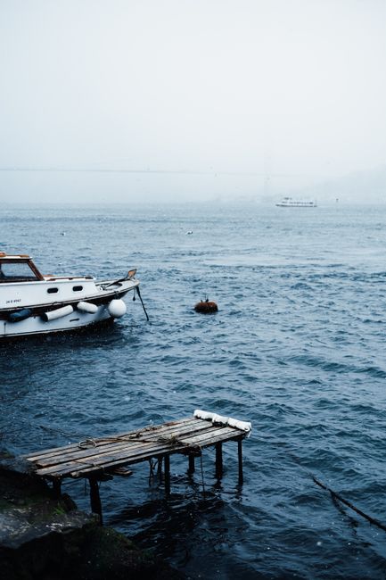 Serene image of a foggy lake with a boat and wooden dock, creating a tranquil atmosphere.