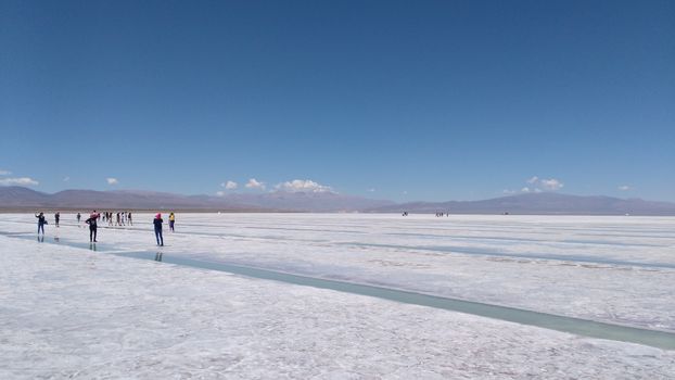 Explore the breathtaking vastness of Salinas Grandes salt flat in Salta, Argentina with a clear blue sky.