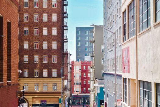 Colorful urban street scene with tall apartment buildings under a bright blue sky.