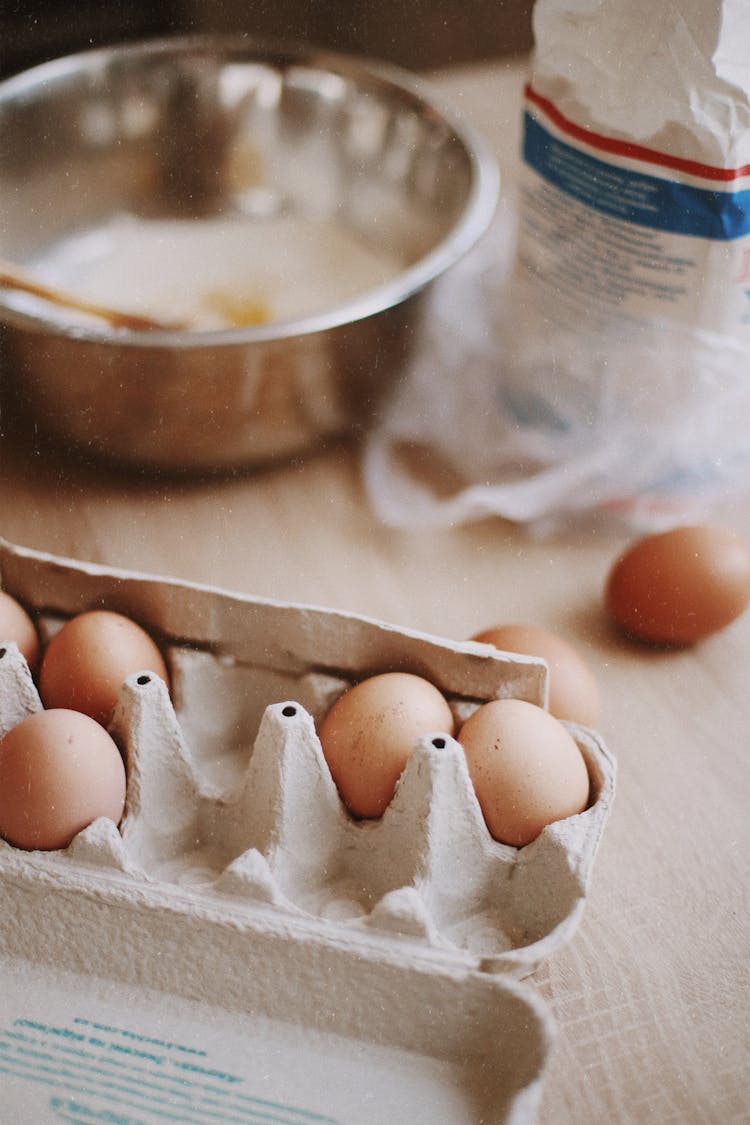 Carton Of Eggs Next To Bowl Of Flour