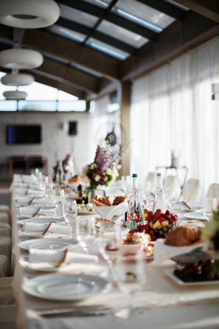 An elegant, sunlit table setting in a restaurant with gourmet food and decoration for a formal event.