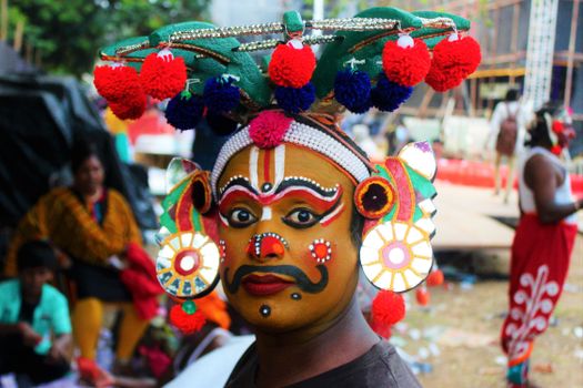 Close-up of a person in vibrant traditional costume with creative makeup and headdress.