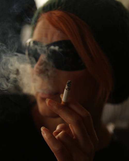 A Woman Smoking Cigarette while Wearing Sunglasses