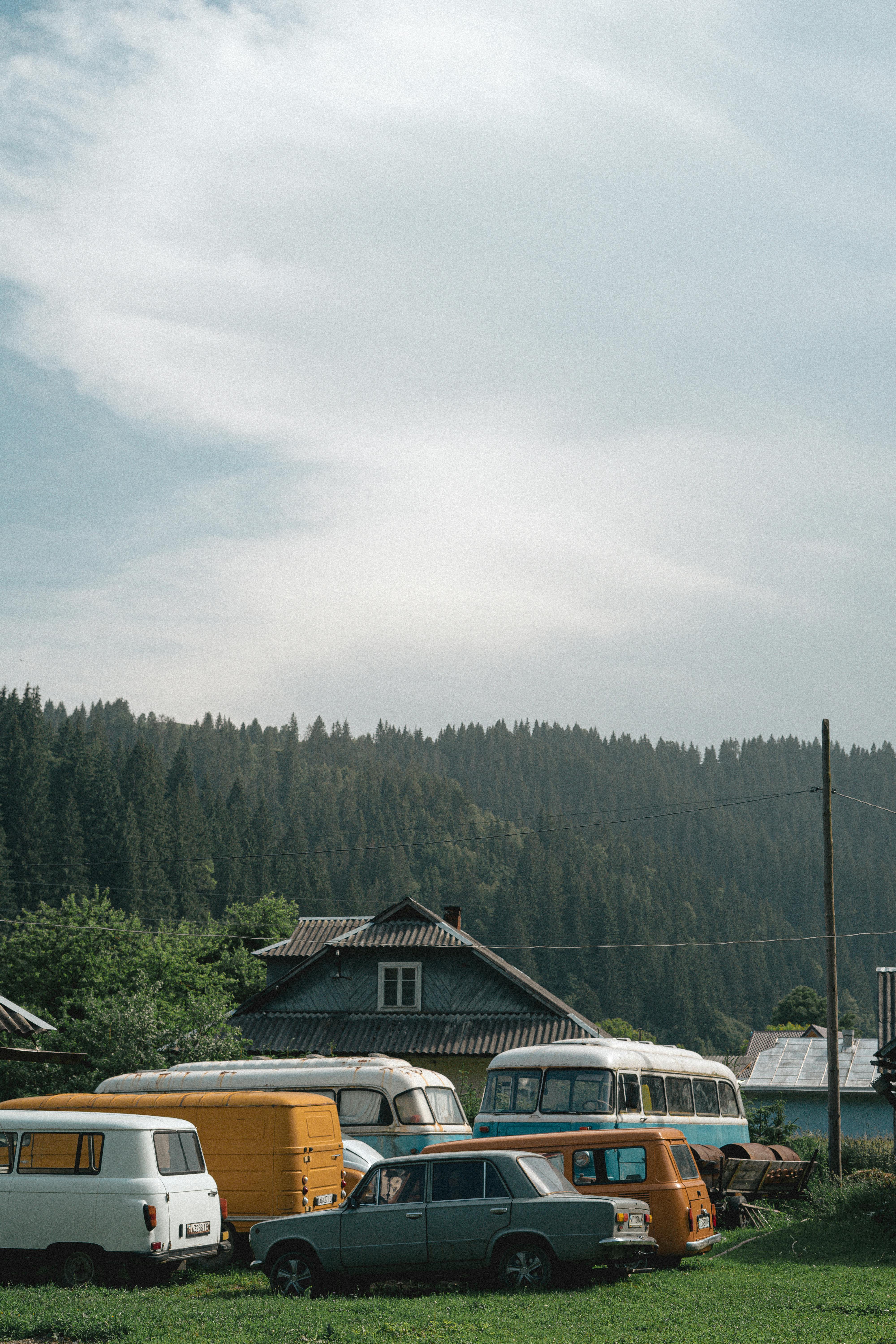 Retro vehicles parked near a rustic cottage in the Carpathians, Ukraine.