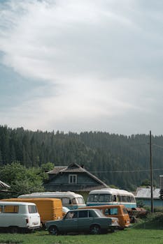 Retro vehicles parked near a rustic cottage in the Carpathians, Ukraine.