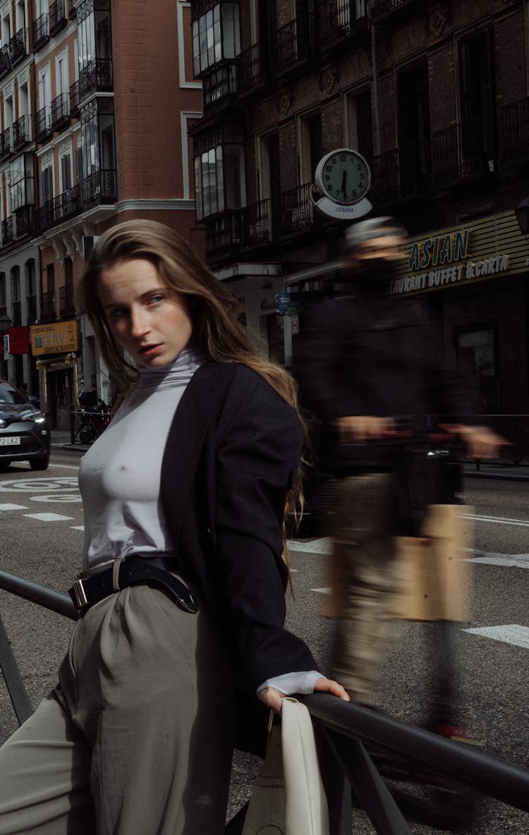 Woman Leaning Against Railing And Man Riding Segway In Town Street