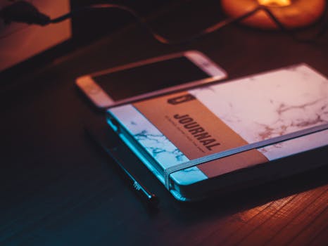 温暖的灯光下，平静的工作空间里摆放着日记、智能手机和笔