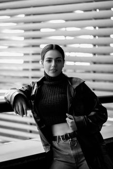 Portrait of a fashionable woman in monochrome, showcasing a confident pose against a modern backdrop.