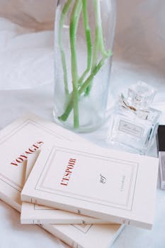 Elegant arrangement of books, perfume, and green stems in Parisian style.