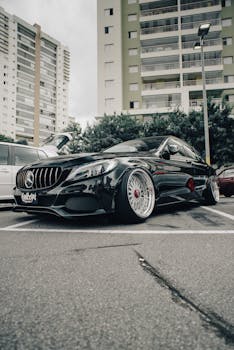 A sleek black luxury car parked in an urban setting with high-rise buildings.