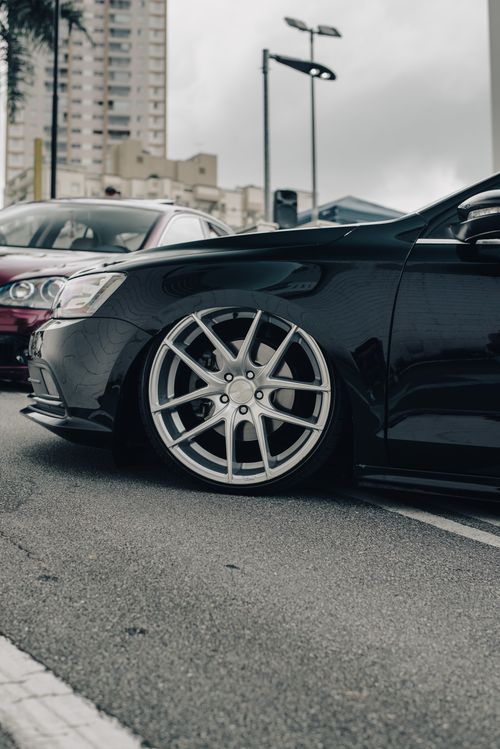 Free Black car with polished alloy wheels parked in a city street, showcasing modern automotive design. Stock Photo