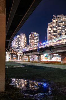 Illuminated Vancouver skyline with reflections, showcasing bridges and skyscrapers at night.
