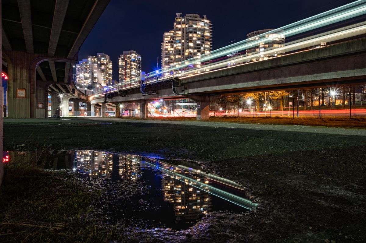 Vancouver nighttime cityscape with light trails on the road and reflections of skyscrapers