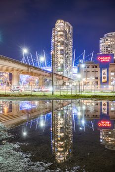 Vancouver cityscape at night featuring Rogers Arena with building reflections.