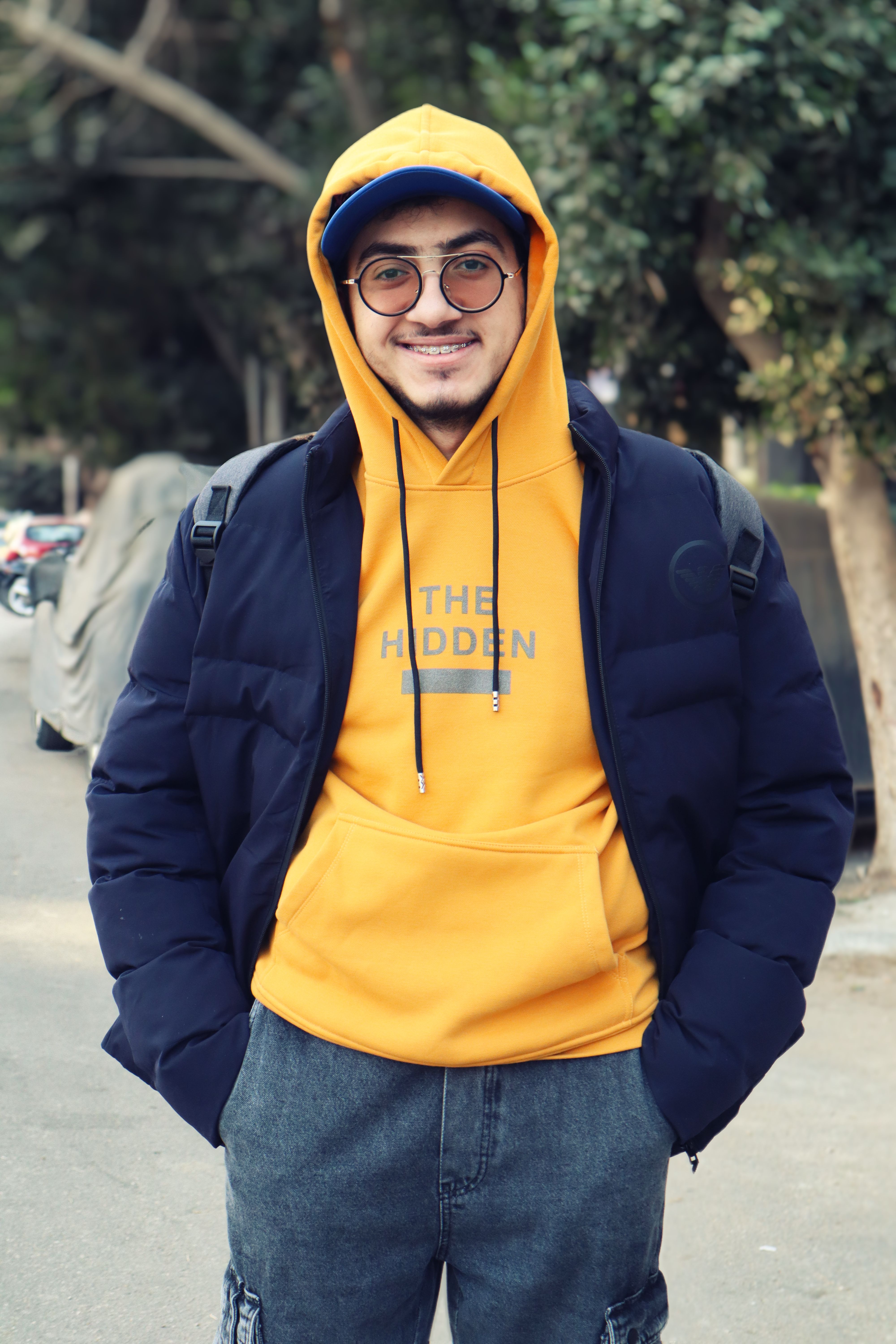 Young man in a vibrant hoodie smiling and standing in a street in Cairo, Egypt.