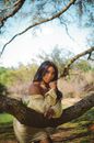 Woman in Yellow Floral Dress Leaning on Tree Branch