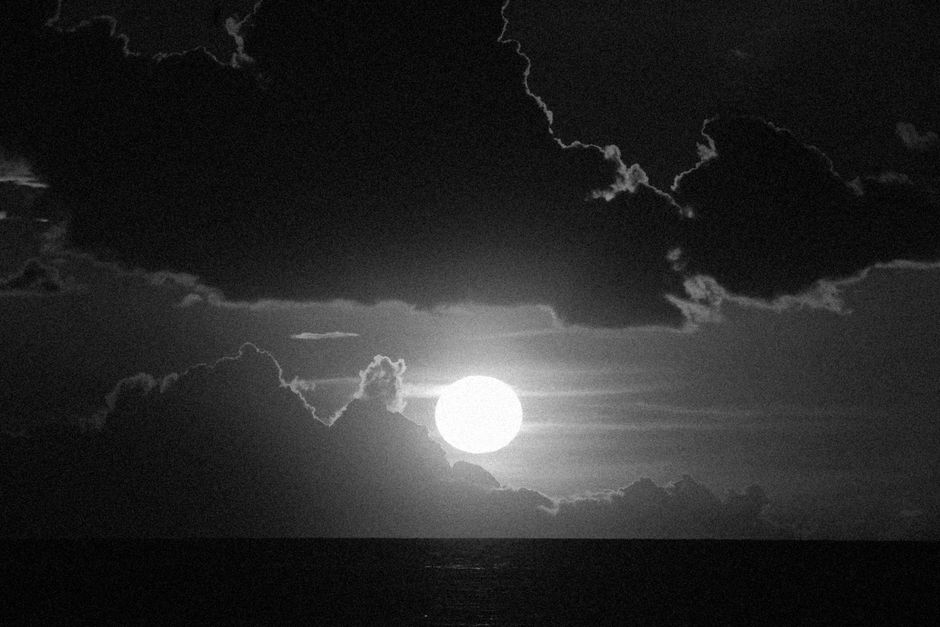 Fotomural Una imagen cautivadora en blanco y negro de la luna rodeada de nubes dramáticas por la noche.