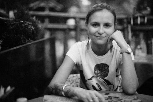 A Grayscale Photo of a Woman in White Shirt with Her Hand on Her Chin